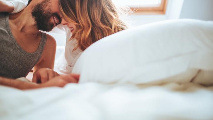 Lovely couple in pyjamas spending Valentine's day in their bed, and sharing their love and affection