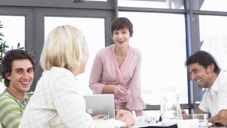 Businesswomen and men laughing sitting at conference table