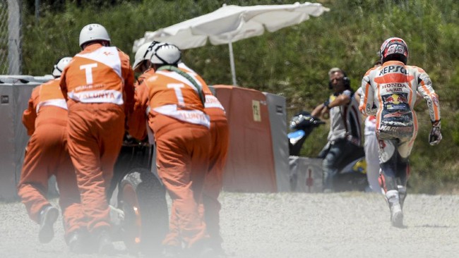 Marc Marquez kembali terjatuh di sesi pemanasan GP Katalonia. Kali ini ia terjatuh lantaran tersandung ketika ingin mengganti motor.