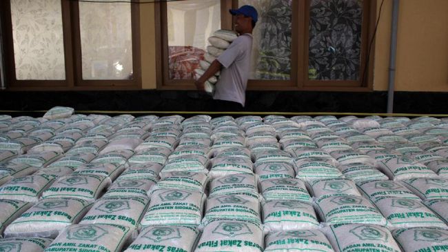 Warga membawa zakat fitrah berupa beras saat pembagian zakat di pendopo Sidoarjo, Jawa Timur, Jumat (23/6). Sekitar 3.000 paket zakat fitrah dari pegawai kabupaten Sidoarjo tersebut diberikan kepada masyarakat yang membutuhkan jelang hari raya Idulfitri. ANTARA FOTO/Umarul Faruq/foc/17.