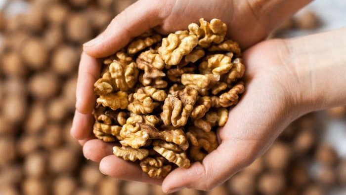 Walnuts with wooden spoon on background
