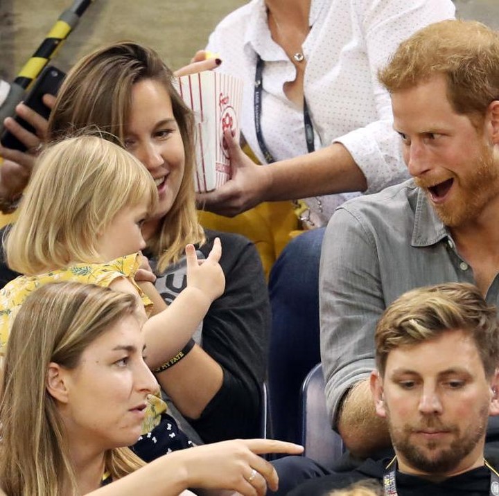 <p>Pangeran Harry yang awalnya hanya diam, akhirnya tidak tahan untuk menggoda balita yang mengambil popcorn-nya. (Foto: Getty Images)</p>