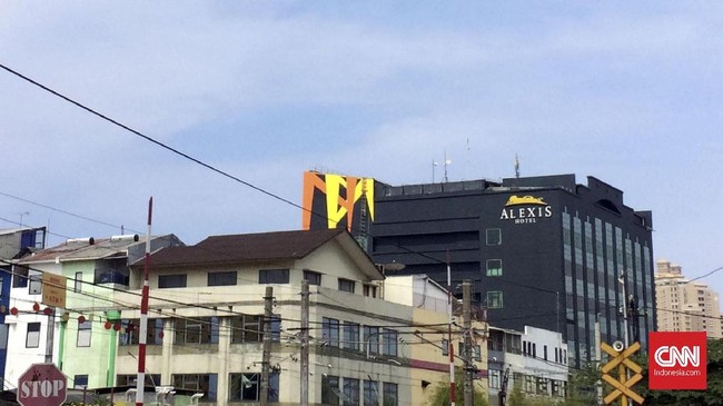 Beberapa taksi terparkir di halaman hotel Alexis. Beberapa tamu hotel yang keluar singgah ke minimarket yang tepat berada di samping lalu masuk hotel.