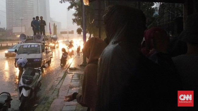 Di bawah guyuran hujan, puluhan peserta aksi memanjatkan doa di depan Mapolda Metro Jaya. Mereka meminta polisi membebaskan dua rekannya.