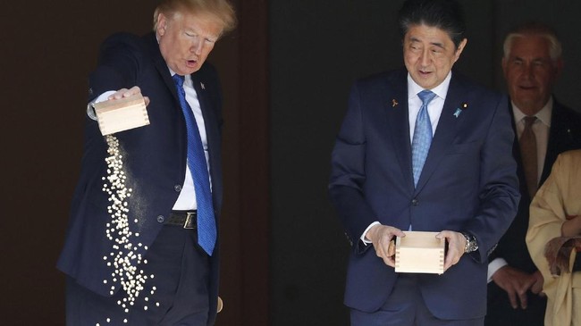 Presiden AS Donald Trump dan PM Jepang Shinzo Abe memberi makan ikan koi sebelum makan siang bersama Kaisar Akihito di Istana Akasaka, Tokyo.