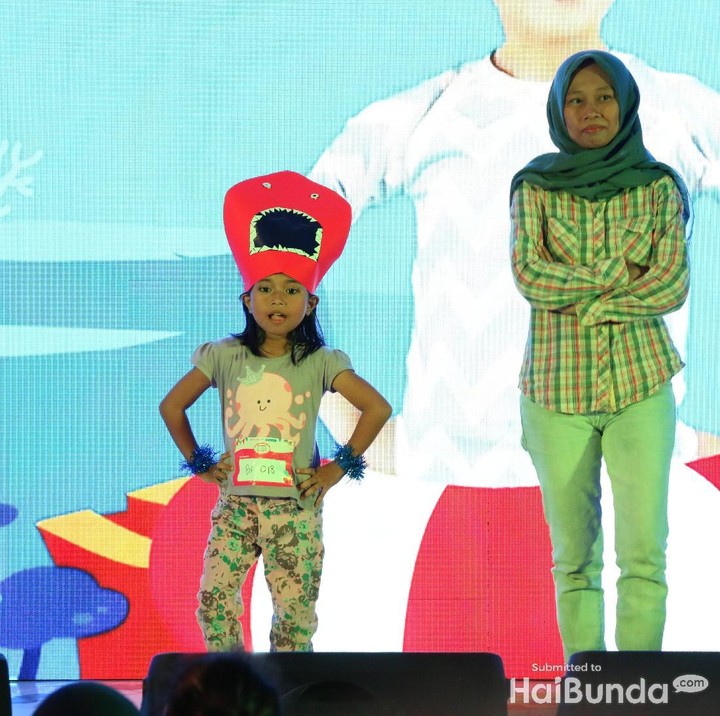 <p>Eh, anak ini pakai topi hiu warna merah.</p>