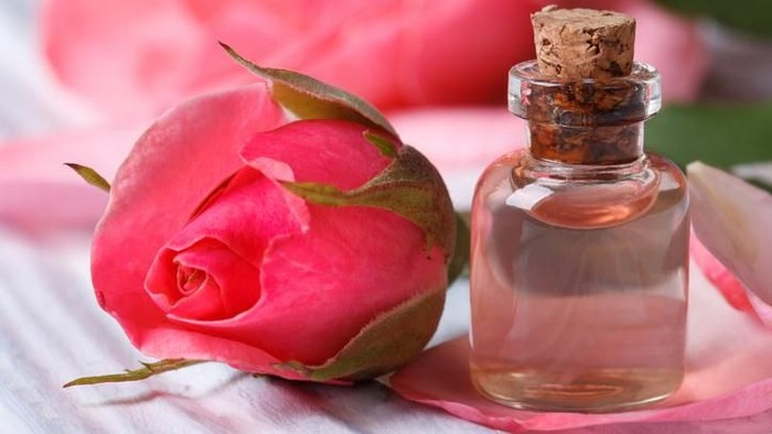 Rose water and pink beautiful flower on a wooden table macro horizontal