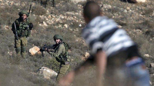 A Palestinian man throws stones towards Israeli soldiers as they enter the northern village of Qusra in the occupied West Bank near Nablus on December 4, 2017.
An Israeli settler shot dead a Palestinian in the occupied West Bank last week after a group of Israelis was targeted by Palestinian stone-throwers, officials said. / AFP PHOTO / JAAFAR ASHTIYEH