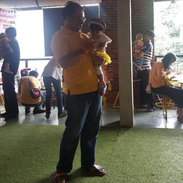 <p>Nah, kalau ini ayah yang menggendong si kecil. Mereka semua kompak berbaju kuning di perayaan ulang tahun anak-anaknya yang pertama, karena mereka berasal dari komunitas Birth Club 2016.</p>