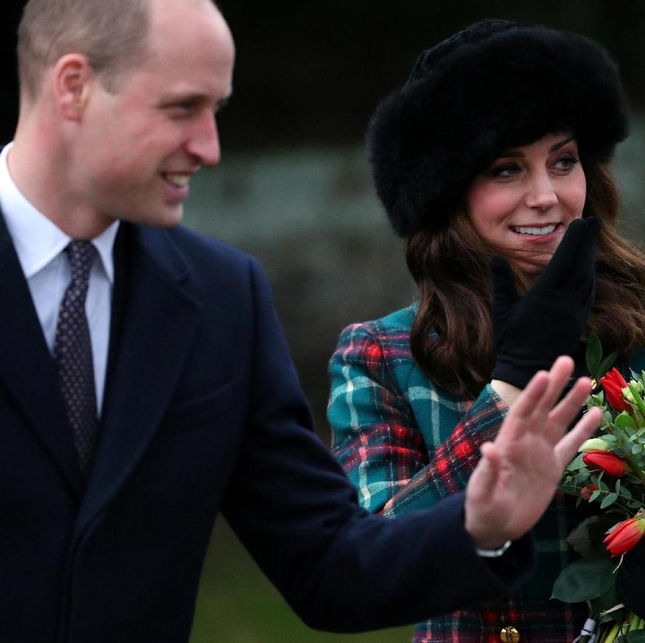 <p>Pada kesempatan lain, Kate Middleton nampak chic mengenakan coat bernuansa hijau dan merah untuk menghadiri acara Natal. Sedangkan Pangeran William terlihat tersenyum sambil melambaikan tangan di sebelahnya. (Foto: Hannah McKay/Reuters)</p>