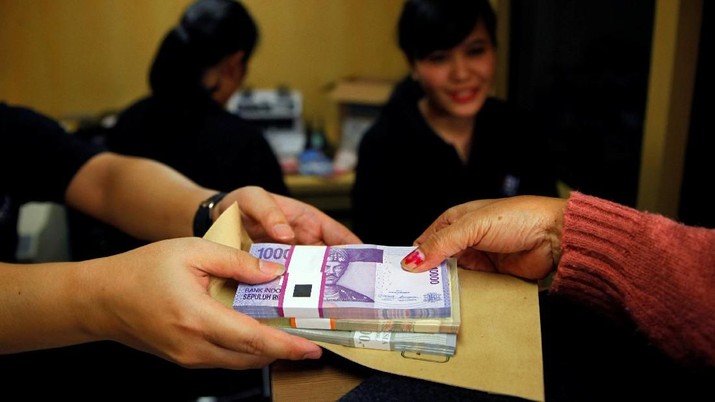 BANK BNI-RESULTS/ FILE PHOTO: A woman holds Indonesian rupiah banknotes at a Bank Negara Indonesia (BNI) mobile bank in Jakarta July 15, 2013. REUTERS/Beawiharta/File Photo