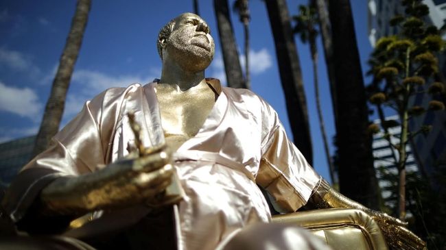 Di dekat lokasi pelaksanaan Oscar 2018 di Hollywood, didirikan patung Harvey Weinstein yang hanya berjubah mandi, duduk di sofa emas dan memegang piala.