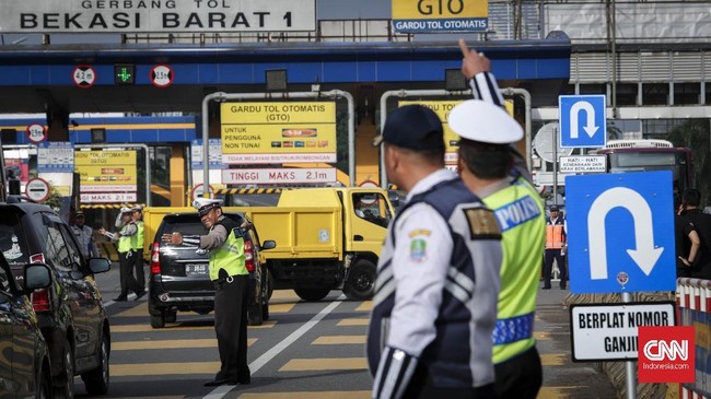 Petugas Dishub dibantu Satpol PP mengarahkan kendaraan berplat genap memasuki lajur gerbang tol Bekasi Barat II di Bekasi.