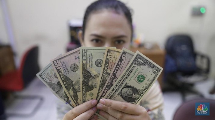 Karyawan menunjukkan pecahan uang dollar di salah satu tempat penukaran uang di kawasan Blok M, Kebayoran Baru, Jumat (16/3/2018). (CNBC Indonesia/Muhammad Sabki)