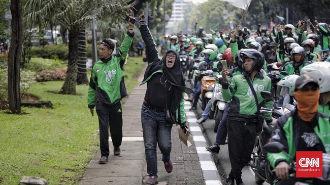 Di seberang Istana para pengemudi ojek online melakukan aksi unjuk rasa, sementara itu motor yang mereka bawa diparkir di sepanjang Jalan Medan Merdeka Barat.