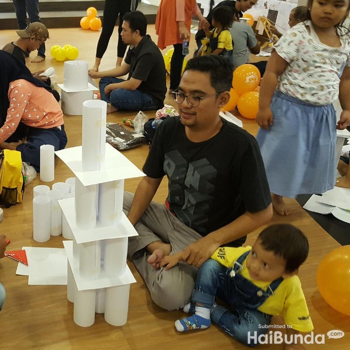 Ini para ayah dan bunda yang sedang ikut lomba membuat bangunan dari kertas dalam rangka ulang tahun anak-anak yang tergabung dalam Birth Club Maret 2016. Si ayah megangin si kecil agar nggak merobohkan bangunan kertas yang sudah tinggi nih. He-he.