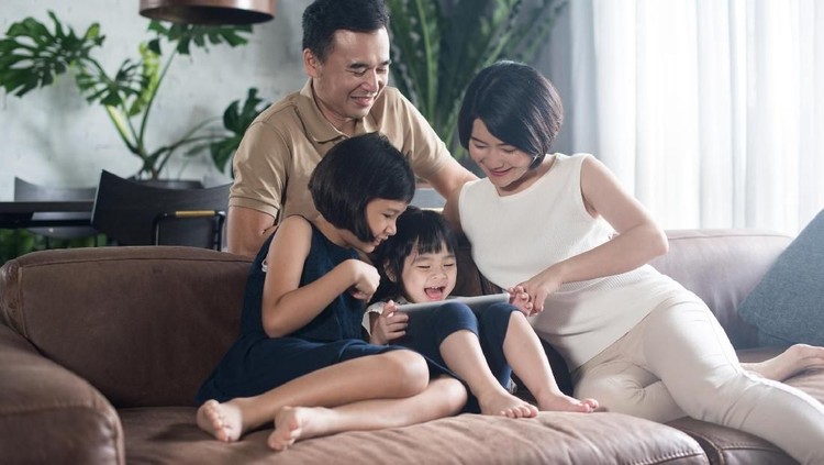 Young Asian family using a tablet in the living room.