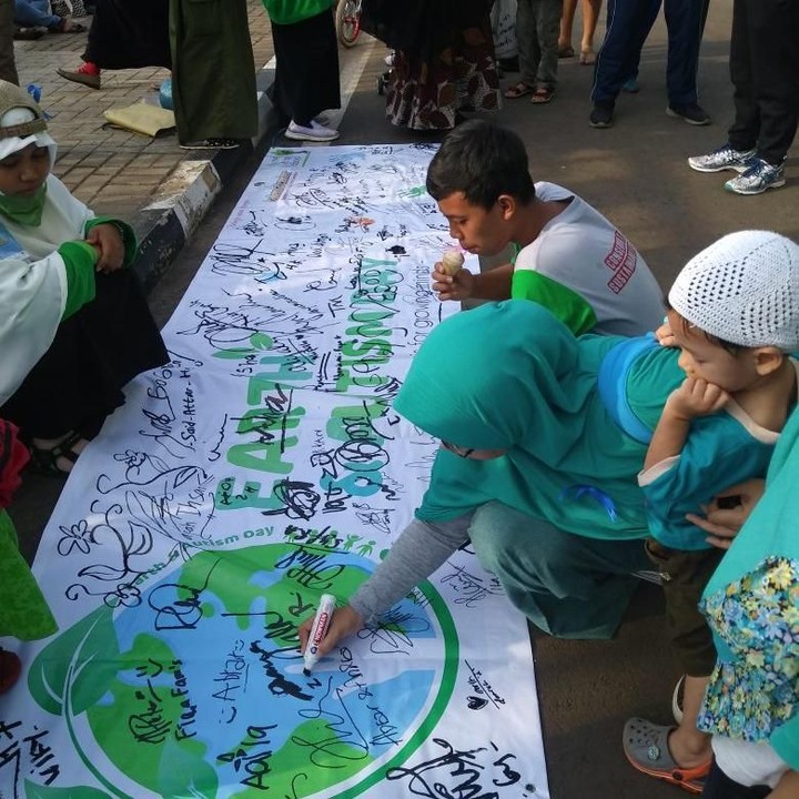 <p>Orang tua murid dan pengunjung CFD menandatangani spanduk sebagai dukungan acara Earth and Autism Day.</p>