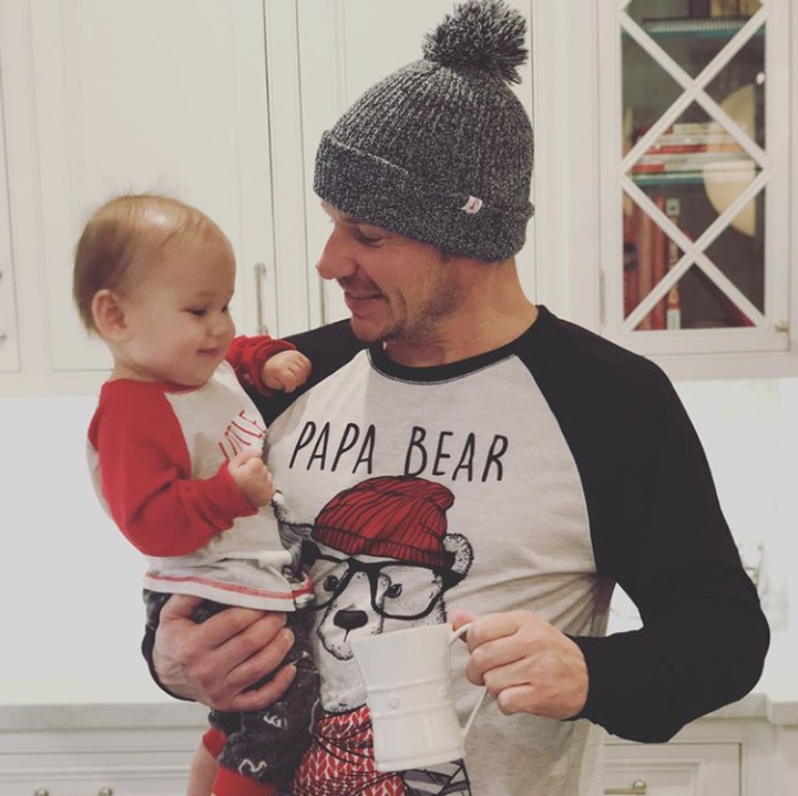 <p>Ayah Nick sedang menggendong si bungsu Phoenix. Ih lucu deh kaos si ayah, tulisannya 'Papa Bear'. (Foto: Instagram @nicklachey)</p>