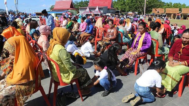 Para anak membasuh kaki ibunya dengan air berisi dedaunan yang disakralkan.