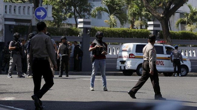 Dua orang polisi yang memegang senjata laras panjang menghampiri laki-laki itu dan langsung menggeledahnya.