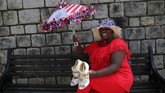 Adinas Perkins dari New Orleans yang berpose membawa sepatu pernikahan, mengaku melihat sosok Pangeran Charles dan Putri Diana di dalam diri Pangeran Harry dan Meghan Markle. Itulah yang membuatnya tak mau melewatkan pernikahan yang satu ini. (REUTERS/Marko Djurica)