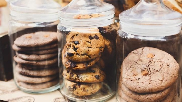 Desserts choice. Cookies and biscuits in glass jars on counter bar for sale. Chocolate drops and chips, oatmeal cookies stacks.