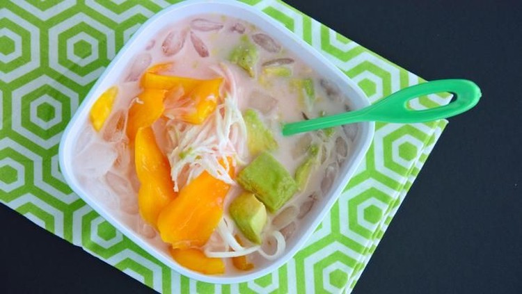 Transparent bowl with condensed milk and teaspoon on wooden table