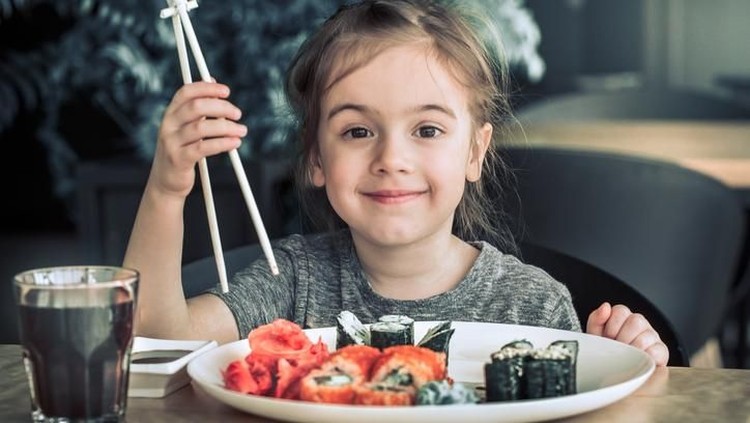 Young girl eating grilled tuna steak and boiled potatoes, Indoors shot of a little girl having a healthy meal decorated with red paprika and looking up at camera.
