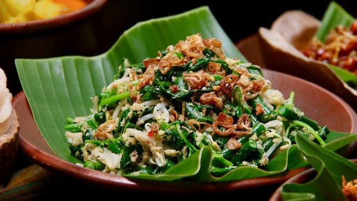 Jukut Urap, the popular Balinese vegetable salad accompanying many Balinese meals, especially Nasi Campur Bali. Cooked spinach, long beans and bean sprouts mixed with spicy grated coconut. Served on an earthenware plate lined with banana leaf.