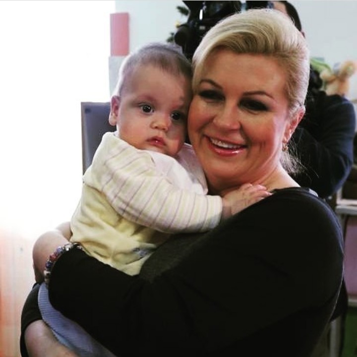 <p>Melempar senyum manis saat berpose bersama seorang bayi. (Foto: Instagram @kolinda_grabar_kitarovic)</p>