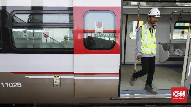 Pekerja melintas di kreta LRT yang terparkir di Stasiun Kelapa Gading Boulevard, Jakarta (15/7).  Proyek kereta dengan panjang lintasan 5,8 km tersebut menghubungkan Kelapa Gading di Jakarta Utara hingga Velodrome di Jakarta Timur.  (CNN Indonesia/ Hesti Rika)