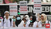 Aksi mereka diawali long march dari IRTI Monas menuju titik demo di Silang Monas, Jalan Merdeka Barat dengan menggunakan snelli (jas dokter) sambil membawa sejumlah poster serta spanduk. Sejumlah dokter muda yang berasal dari berbagai daerah di Indonesia ikut aksi yang digelar Kamis siang, 19 Juli 2018. (CNN Indonesia/Andry Novelino)