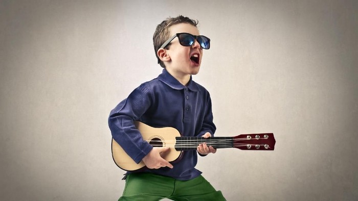 Boy is singing with a guitar in his hands