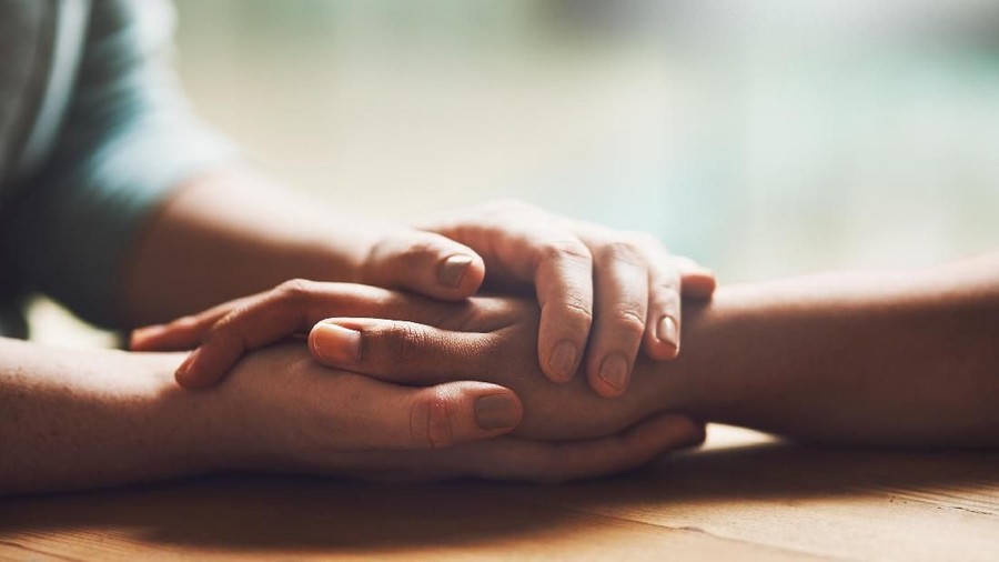 Shot of two people holding hands in comfort