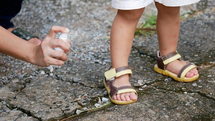 Mother spraying insect or mosquito repellents on skin girl, mosquito repellent for babies, toddlers that will protect your children from mosquitoes and other insects.