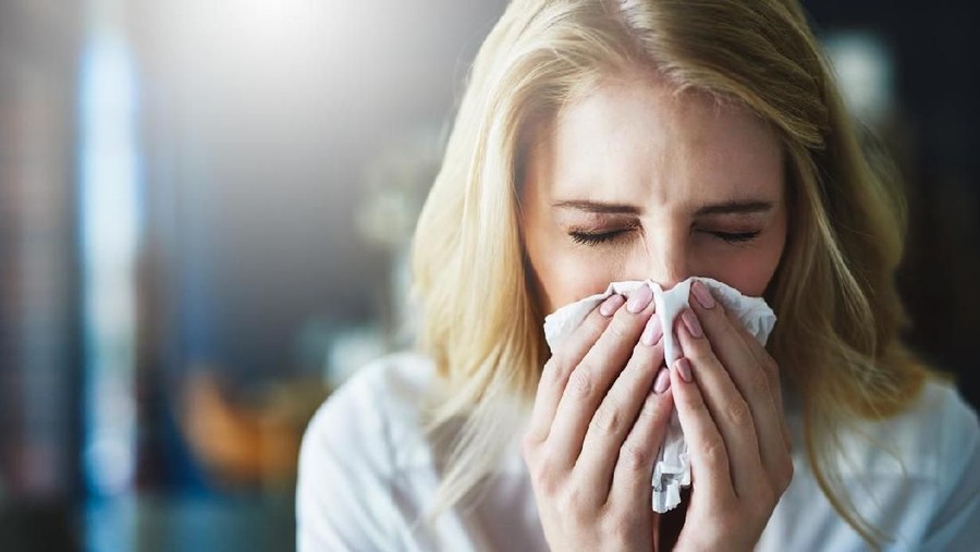 Cropped shot of a young businesswoman blowing her nose with a tissue in the office