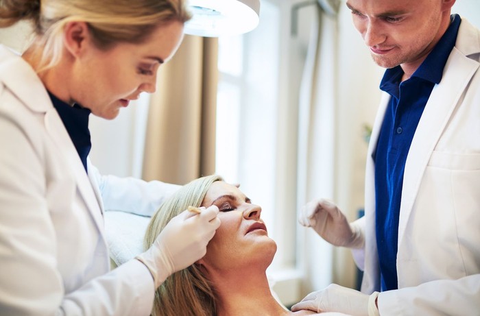 Close-up Of A Surgeon Drawing Perforation Lines On Young Woman's Face For Plastic Surgery