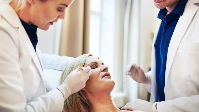 Close-up Of A Surgeon Drawing Perforation Lines On Young Woman's Face For Plastic Surgery