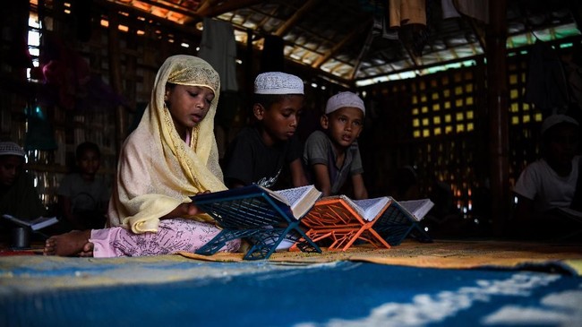In this photograph taken on August 12, 2018, Saleema Khanam (L), 8, studies inside a makeshift madrassa (Islamic seminary) with other boys in Kutupalong camp, in Ukhia near Cox's Bazar.
Islamic seminaries or madrassas, catering to Rohingya children driven from Buddhist-majority Myanmar by a wave of genocidal violence, are springing up in the world's largest refugee camp in Bangladesh since a massive influx of Rohingya Muslims last year. Formal schooling, which suggests a permanent presence, is not allowed in the camps. For many children, the madrassas are the only places to learn. / AFP PHOTO / CHANDAN KHANNA