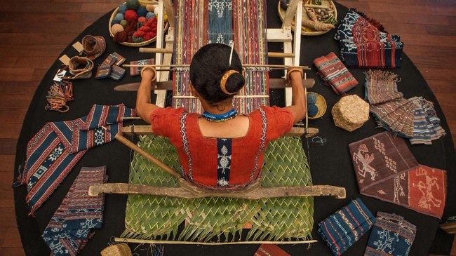 Perajin menenun kain di Paviliun Indonesia di sela ajang Pertemuan Tahunan IMF-World Bank Group 2018 di Nusa Dua, Bali, Senin (8/10). Sebanyak 150 UMKM dari 64 kabupaten/kota di seluruh Indonesia menampilkan hasil kerajinan mereka pada acara tahunan IMF-World Bank Group 2018.ANTARA FOTO/ ICom/AM IMF-WBG/Afriadi Hikmal/wsj/2018.