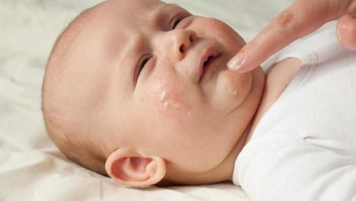 Female hand applying the cream on baby's face
