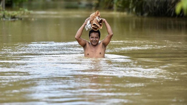 An Indonesia man wades through floodwaters following heavy rains in Teunom in Aceh province on October 16, 2018. (Photo by CHAIDEER MAHYUDDIN / AFP)