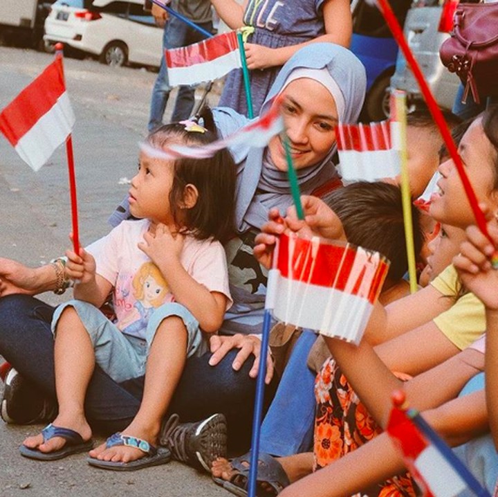 Untuk Steffy Burase, bahagia itu sesederhana duduk bareng anak-anak sambil memegang bendera kayak gini. He-he-he. (Foto: Instagram/ @steffyburase)