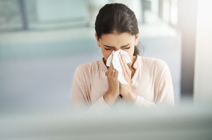 Sick Woman Sneezing in to Tissue Paper
