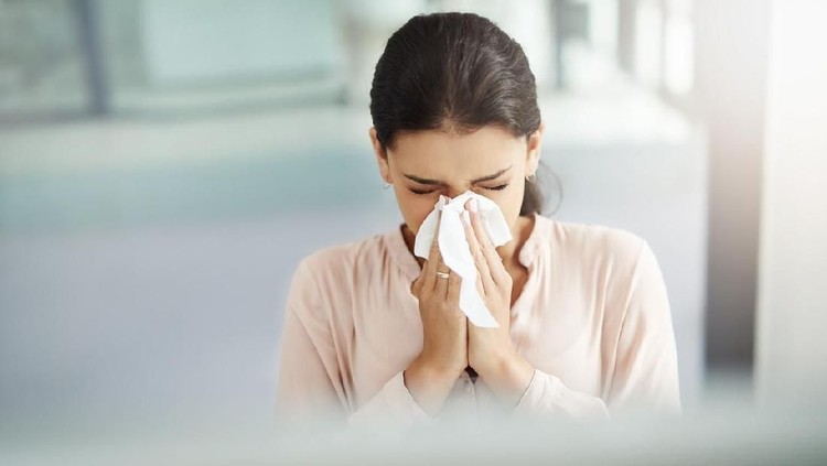 Sick Woman Sneezing in to Tissue Paper