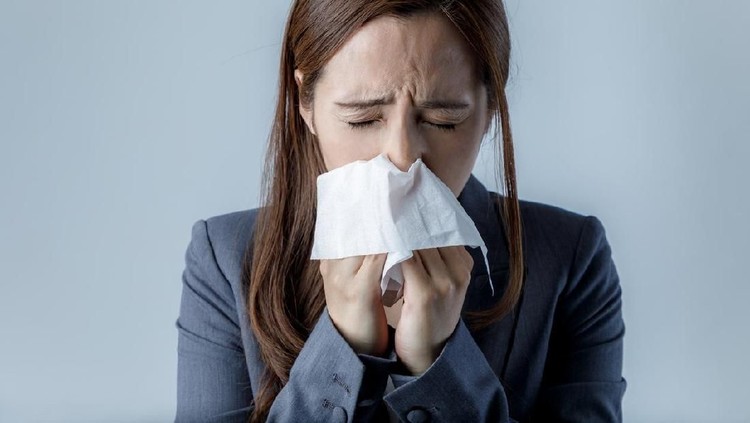 Sick Woman Sneezing in to Tissue Paper