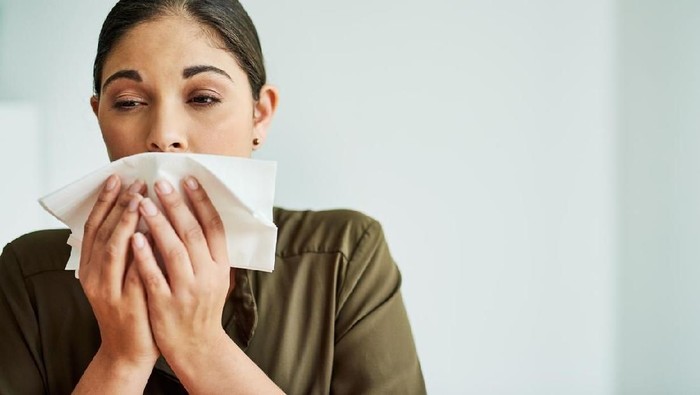 Sick Woman Sneezing in to Tissue Paper