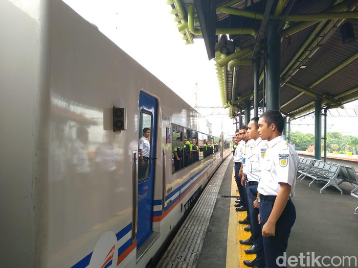 Porter dan pegawai PT KAI menunduk saat kereta berangkat