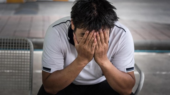 Man fired from job sitting hold the head with hand and worried stressed face expression outside office